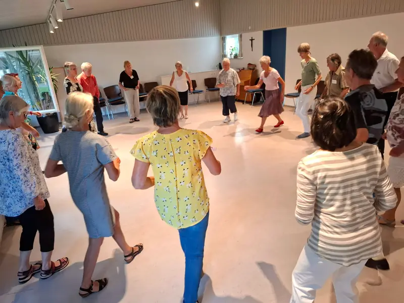 Tänzerinnen und Tänzer bewegen sich gemeinsam im großen Kreis durch den hellen Saal in Füssen