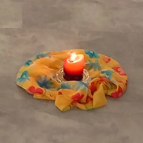 Eine brennende Kerze auf einem bunten Tuch in der Mitte des Tanzkreises